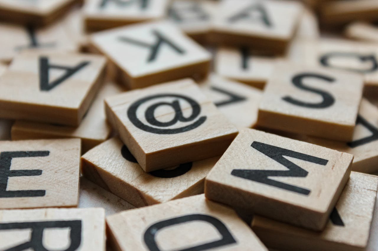A detailed close-up of wooden Scrabble tiles featuring various letters and symbols.